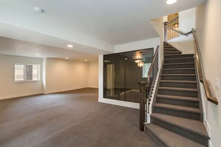 A dry, finished basement with a staircase and neutral wall finishes
