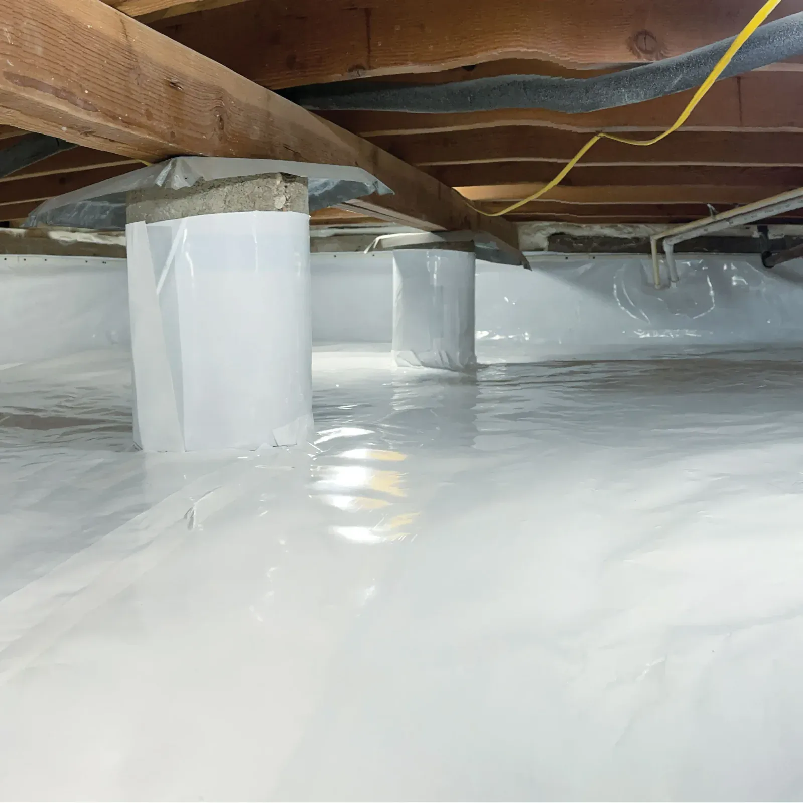 A completed crawl space encapsulation, with heavy vapour barrier sealed across the ground and wrapped up the support piers