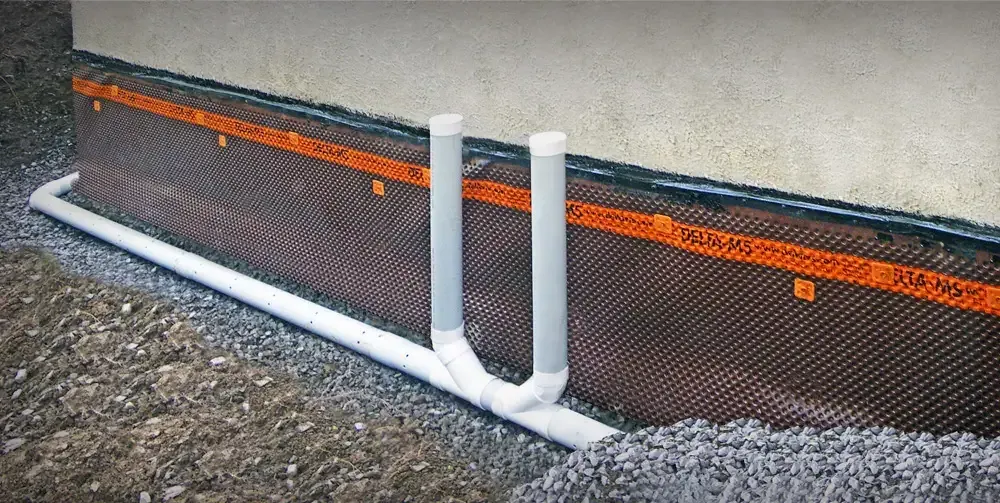 An interior perimeter drainage system with dimple board up the wall and cleanout risers set into fresh concrete