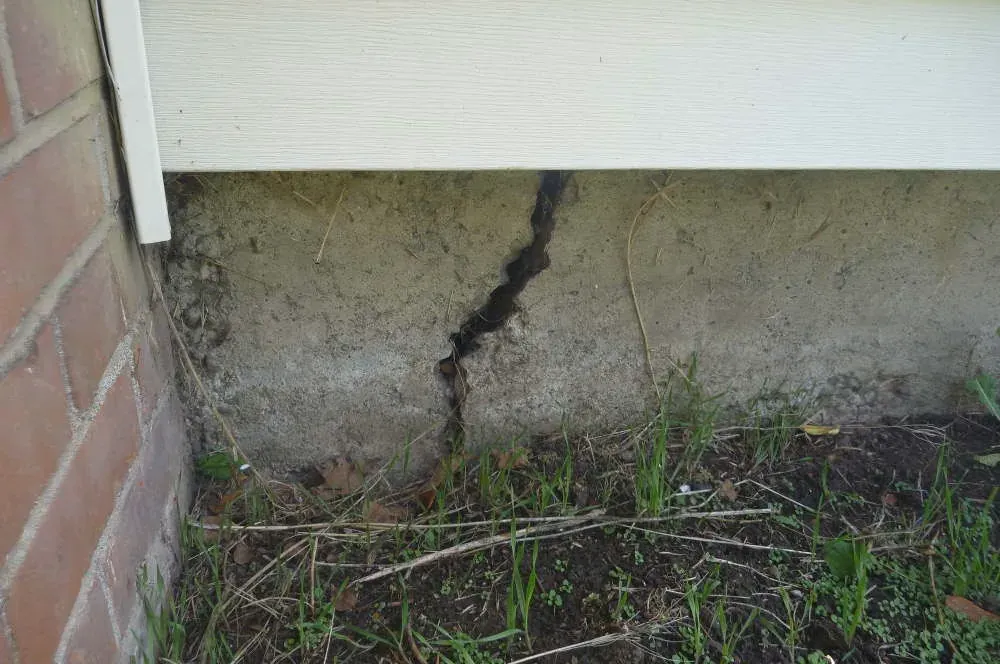 A stair-step crack running through the mortar joints of a concrete block foundation wall