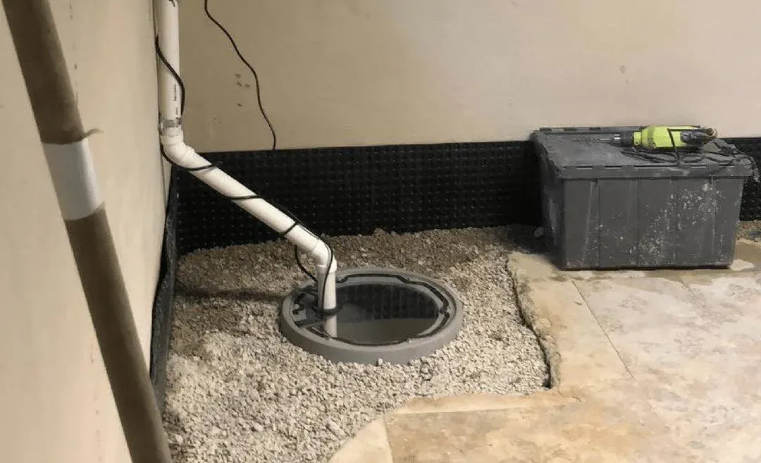 A sump basin set into a basement floor with rigid discharge plumbing and a check valve