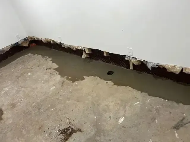 Standing water along the joint where a basement floor meets the foundation wall